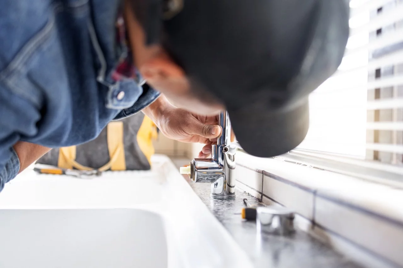 Loodgieter die een kraan repareert, loodgieterswerk en onderhoud met man, handarbeid en woningrenovatie met tr.
